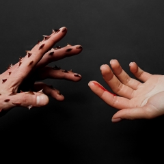 One hand with attached thorns in hurting the other. Gender-based violence concept.